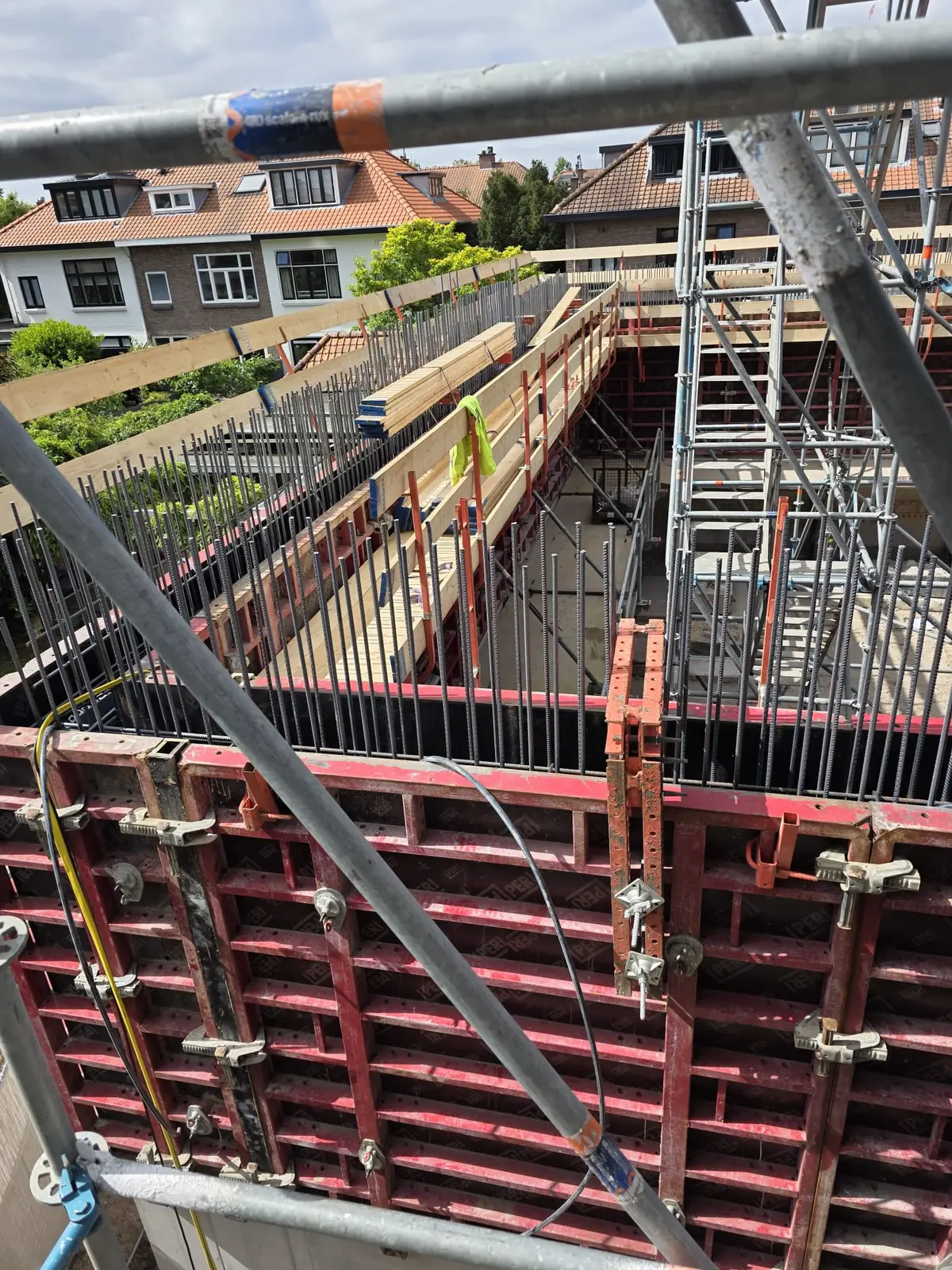 Rode systeembekisting met schoren en spindels rond een betonwand op de bouwplaats